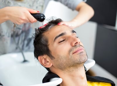 Einem Mann werden in einem Schönheitssalon die Haare gewaschen